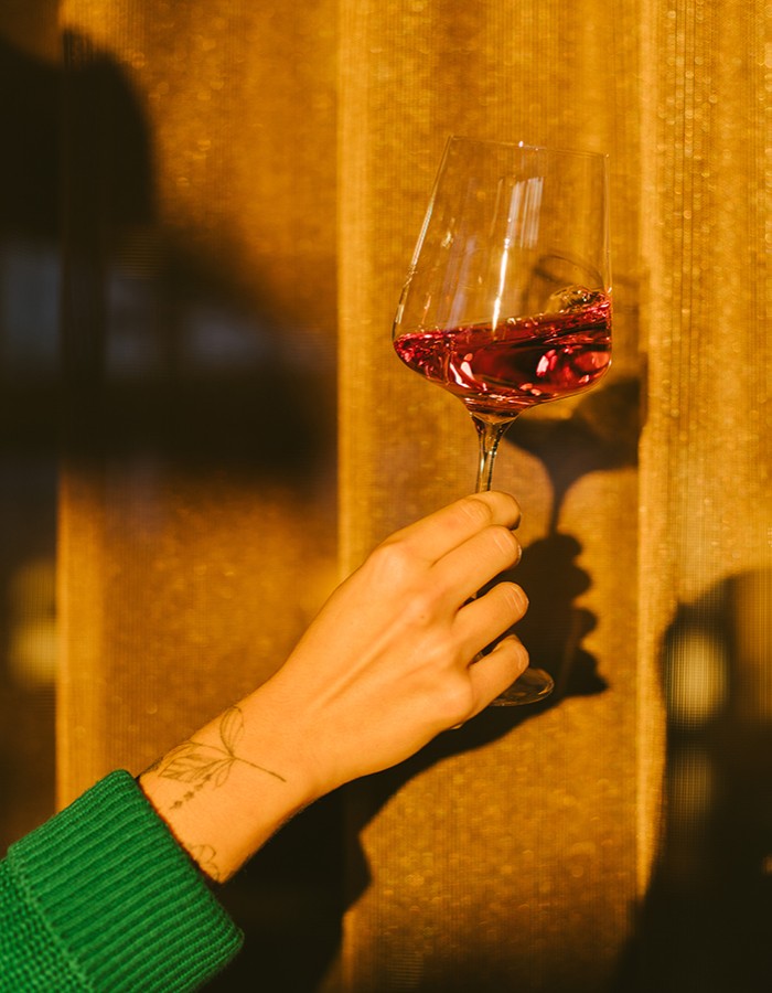 Hotel Reiters Supreme - Hand hält ein Glas Rotwein in die Sonne