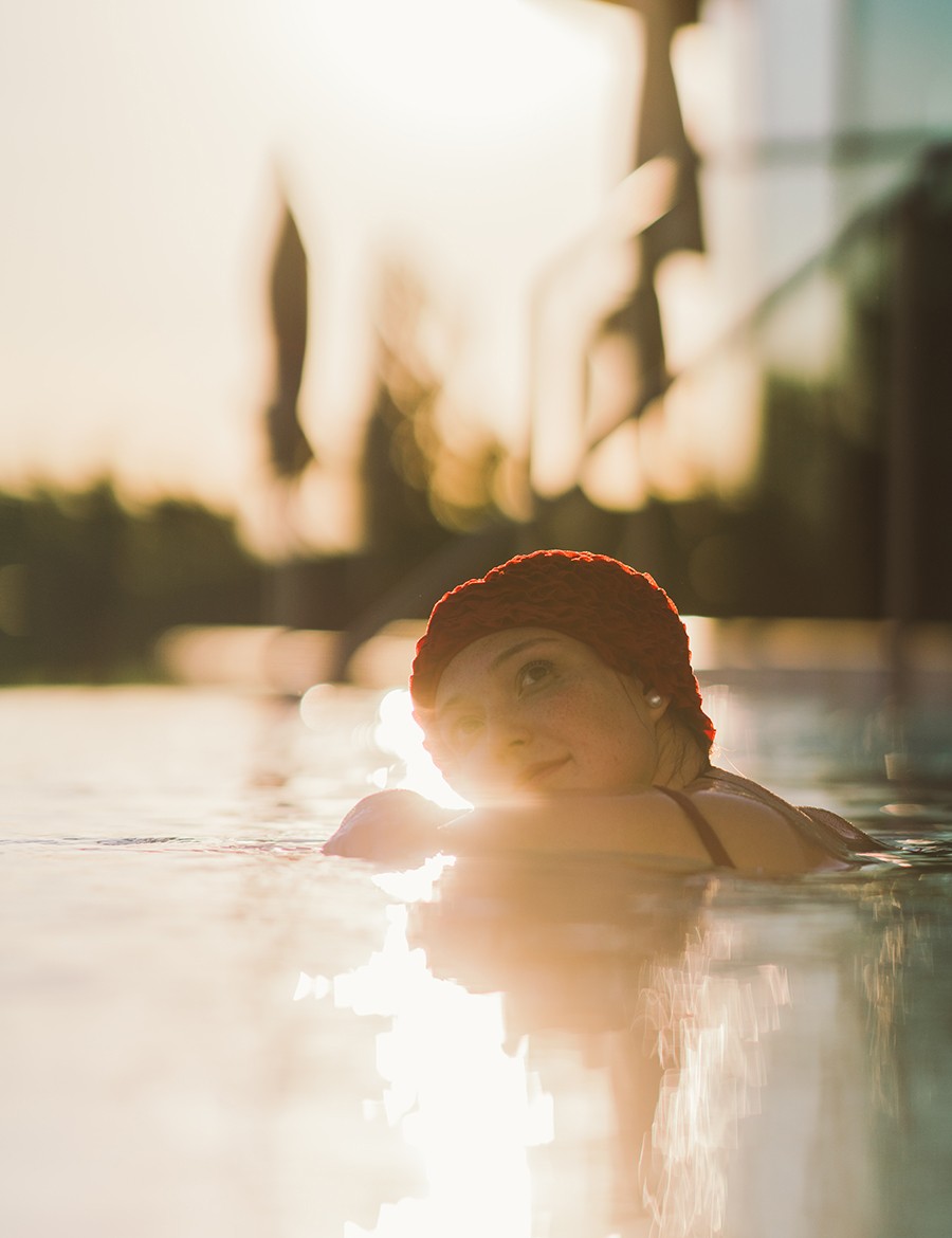 Hotel Reiters Supreme - Frau mit Badehaube genießt die Sonne im Pool