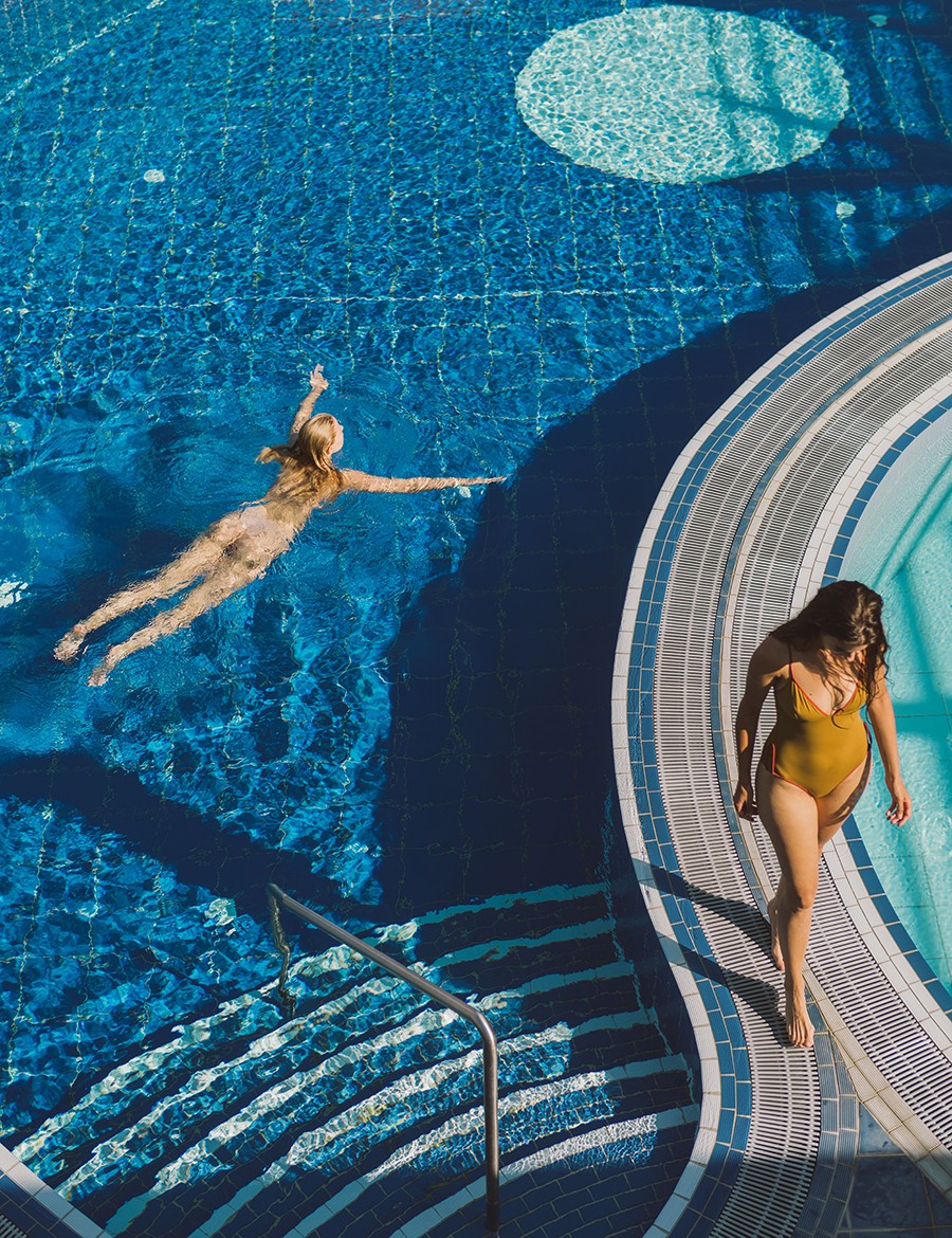 Hotel Reiters Supreme - Woman swims in the Yin-Yang pool, second woman walks along the edge of the pool